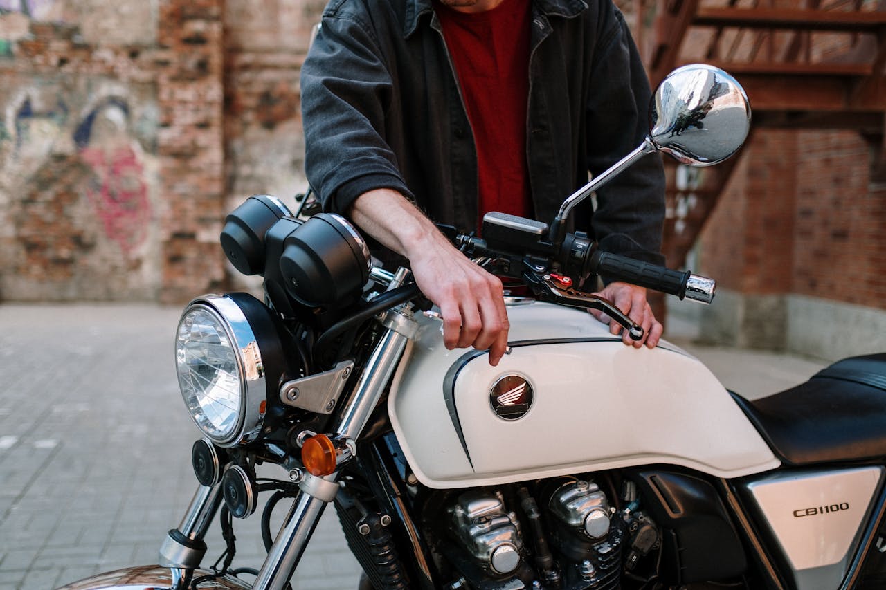 Technician working on a motorcycle outdoors, focusing on maintenance and adjustments.